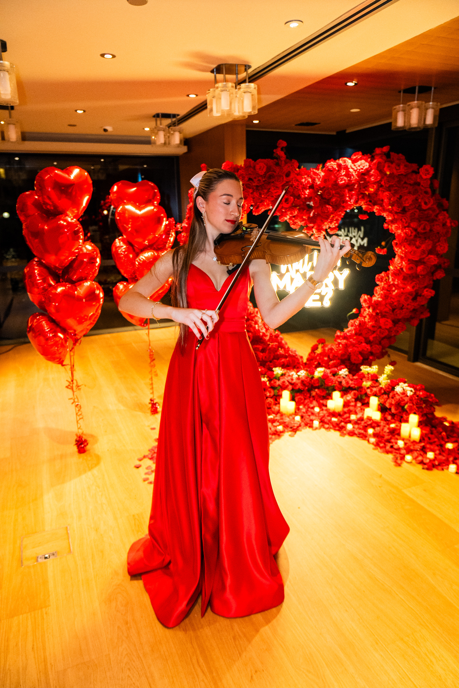 Tali in red ball gown in front of proposal set up